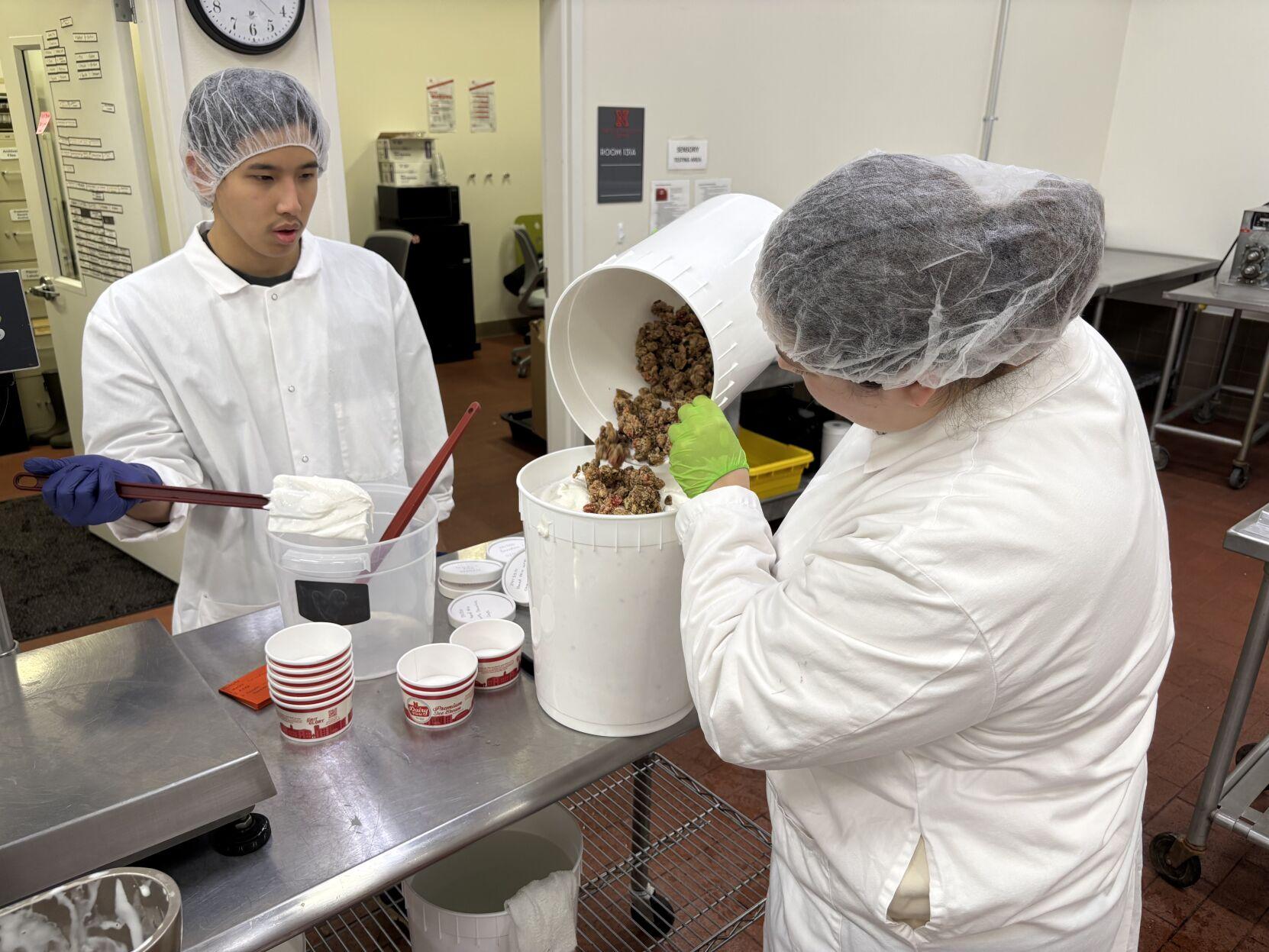   Emma Abernathy, a senior biological systems engineering major from Rusk, Texas, pours cake and fruit pieces into vanilla ice cream as Will Tessalee, a sophomore mechanical engineering major from Bangkok, Thailand, waits to mix the ingredients together. The University of Nebraska–Lincoln student workers make ice cream for a client in the Food Processing Center’s dairy plant. The FPC has 20 employees and around 20 student workers. | Maddie Hansen/Nebraska News Service