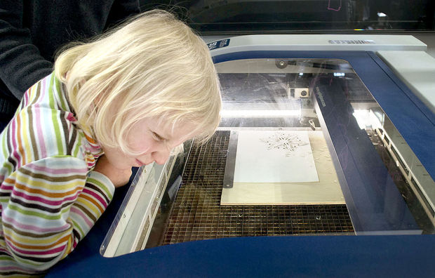 Lauren Zeleny scrutinizes the innards of a laser-cutting machine as it works on a paper snowflake on Saturday at Nebraska Innovation Campus.