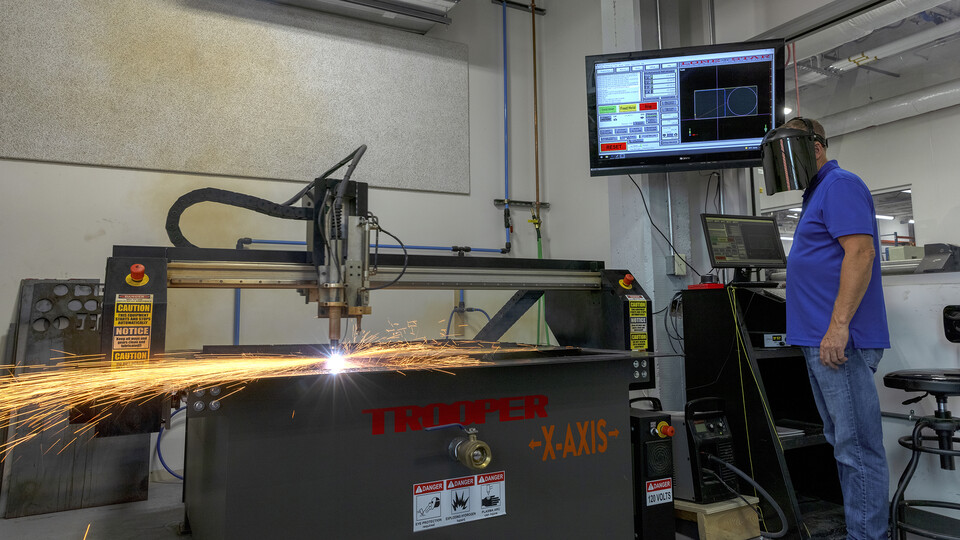 Jerry Reif, shop manager at Nebraska Innovation Studio, watches as a plasma cutter cuts through steel. 