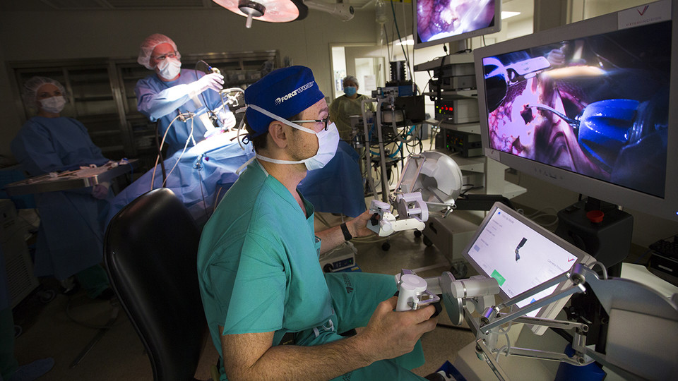 UNMC's Dmitry Oleynikov operates a surgical robot as Shane Farritor (second from left), an engineering professor at the University of Nebraska-Lincoln, adjusts the robot's camera. The researchers' company, Virtual Incision Corp., has received new funding to support human trials and potential commercial approval for the robotic. 