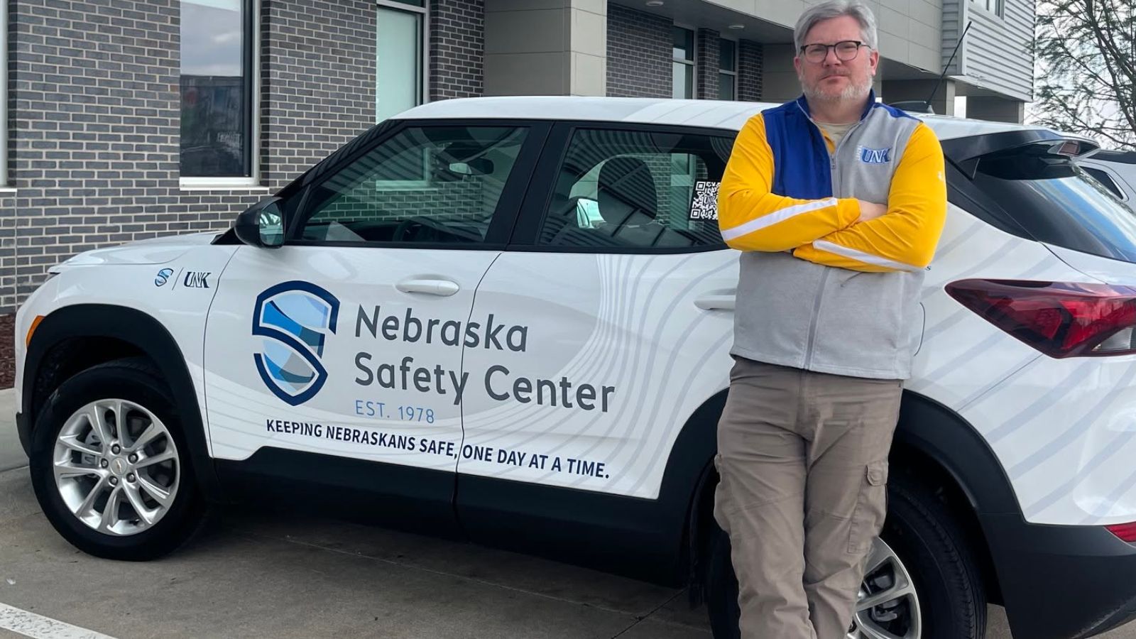 Man standing next to a white SUV with Nebraska Safety Center branding.