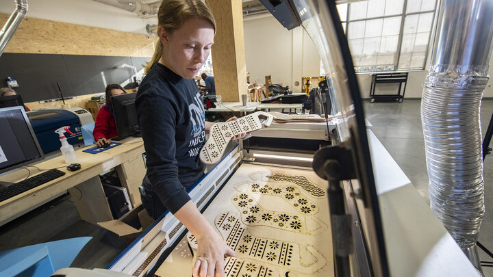 Carly Brotherson pulls sock blocks from the laser cutter at Nebraska Innovation Studio Nov. 25. Brotherson made the sock blocks for a yarn store, which requested the project through the new 'Request a Maker' button, which matches makers to projects. 