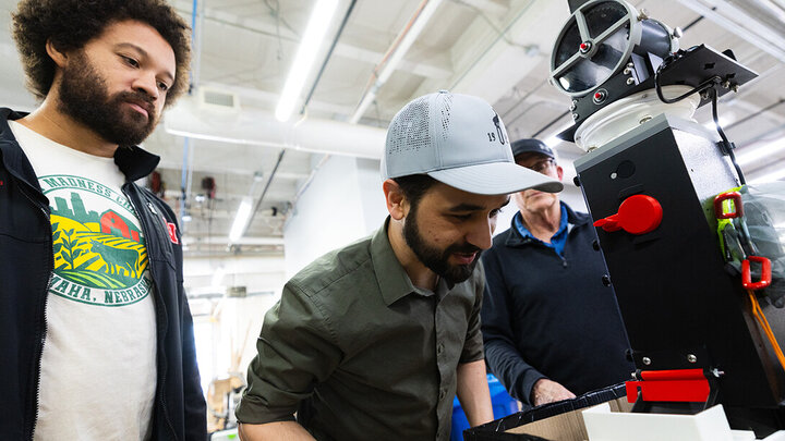 Group of people working with a machine in a bright industrial workshop.
