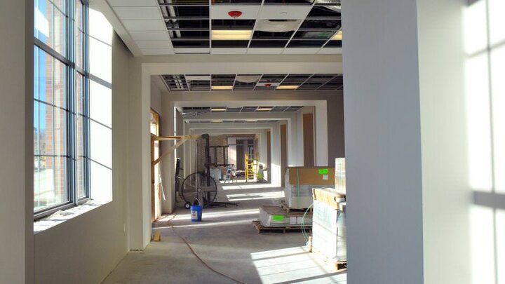 A construction worker sands drywall in a redesigned 4-H Building hallway on Nebraska Innovation Campus.