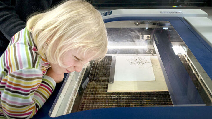 Lauren Zeleny scrutinizes the innards of a laser-cutting machine as it works on a paper snowflake on Saturday at Nebraska Innovation Campus.
